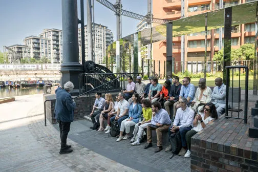 Group of participants sitting down outside listening to professor explaining the development 